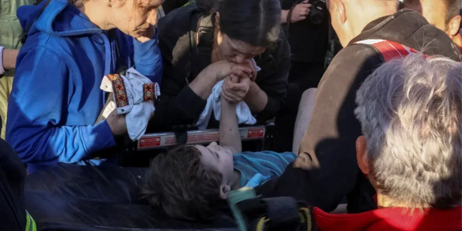 Мати тримає за руку сина, врятованого з-під завалів у Львові